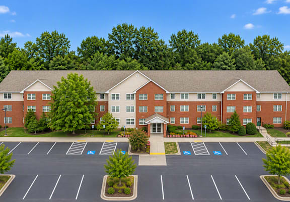 A large red brick building with a parking lot in front.