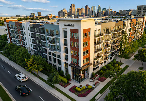 A street view of a multi-story building with cars parked on the side of the road.