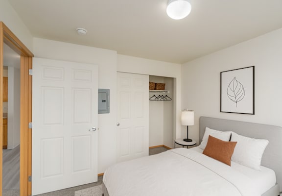 A bedroom with a bed, nightstand, and lamp.