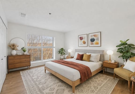 A bedroom with a large bed, a wooden dresser, a chair, and a rug.