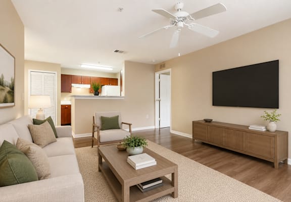 A living room with a white couch, a wooden coffee table, and a flat screen TV mounted on the wall.