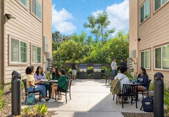 A group of people are sitting around a table outside of a building.