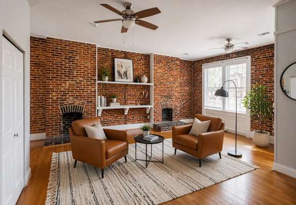 A living room with a brick wall and two chairs.