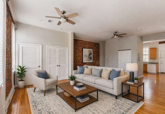 A living room with a white couch, a coffee table, and a ceiling fan.
