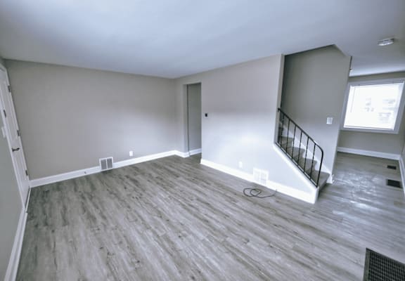 an empty living room with wood flooring and a staircase