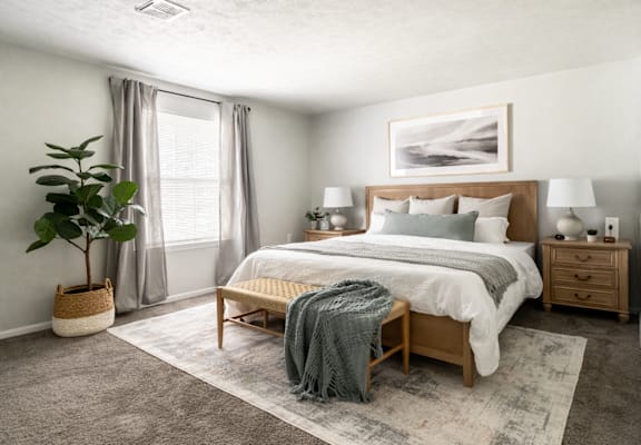 A bedroom with a large bed, a nightstand, and a plant.