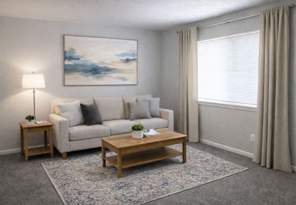 A living room with a white sofa, a wooden coffee table, and a painting on the wall.
