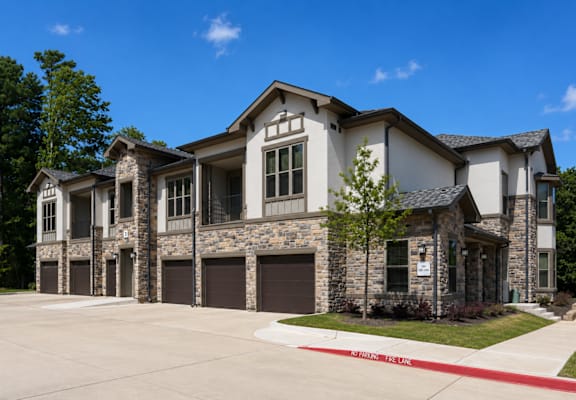 Apartment building with attached garages and landscaped grounds at Auberge of Tyler.