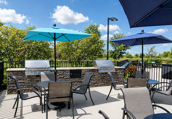 A patio with chairs and tables under umbrellas.