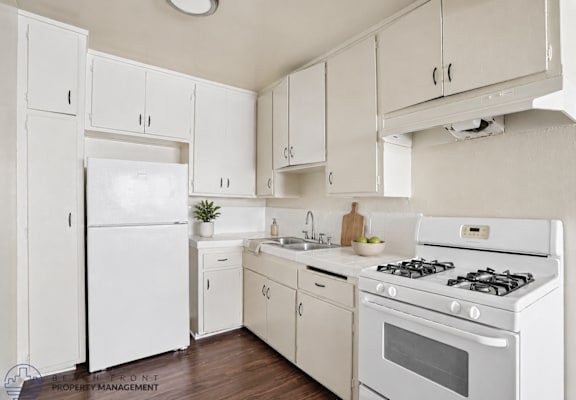 A white kitchen with a refrigerator, oven, and sink.