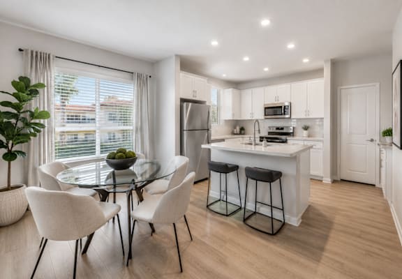 A modern kitchen with a glass table and white chairs.