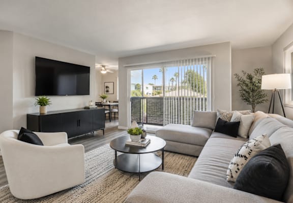 A modern living room with a grey sofa, a white armchair, and a black and white patterned cushion.