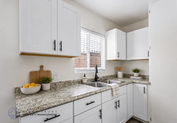 A kitchen with white cabinets and a granite countertop.