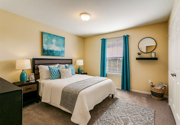 A bedroom with a bed, nightstands, and a painting on the wall.