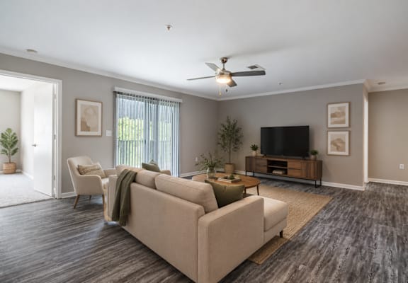Bright open-concept living room at Lancaster Place Apartments in Calera, Alabama featuring wood-style flooring, abundant natural light, and a spacious layout.