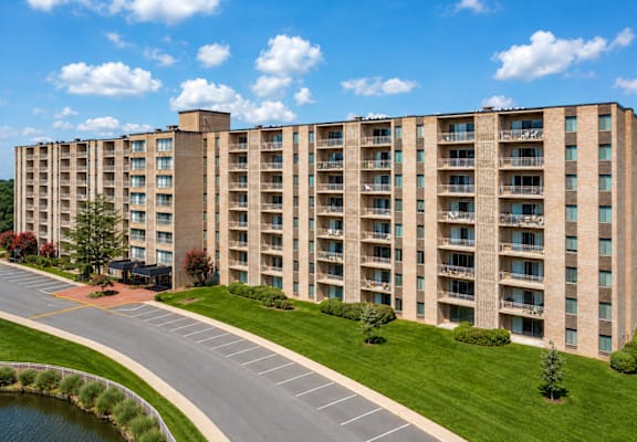A large apartment building with a pond in front of it.