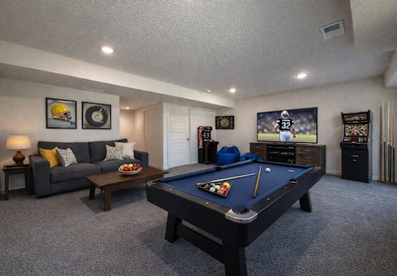 A pool table is in the middle of a living room.