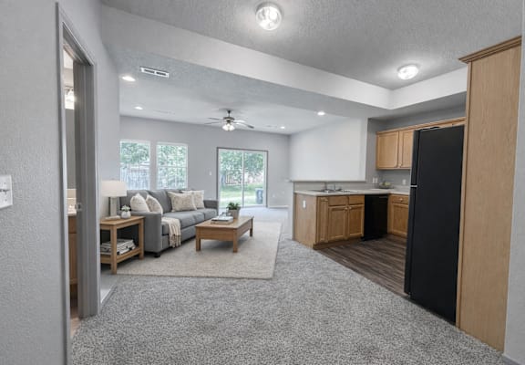 A modern kitchen and living room with a black refrigerator.