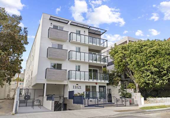 a white apartment building with balconies and trees in front of it