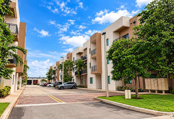 A sunny day at a residential complex with cars parked in the driveway.