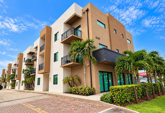 A modern building with balconies and green doors.