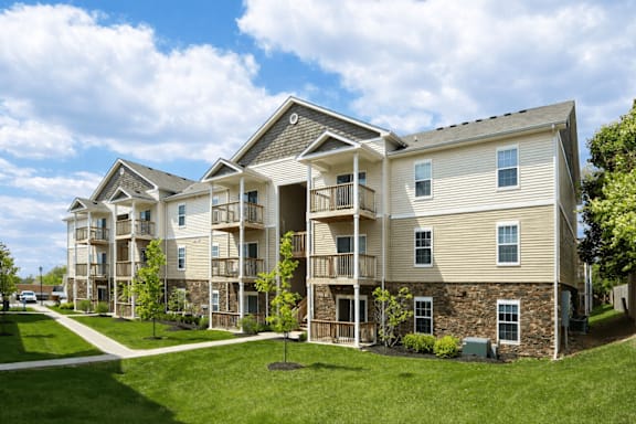 A large apartment complex with multiple balconies and a green lawn in front.