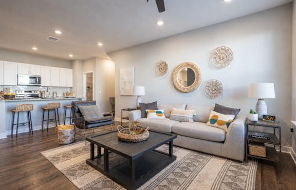 A modern living room with a grey couch, a coffee table, and a bar area in the background.