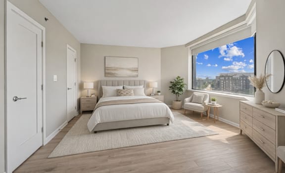 A bedroom with a large bed, a window with a view, and a potted plant.