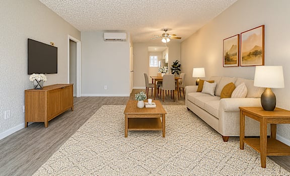 A living room with a white couch, wooden coffee table, and a flat screen TV.