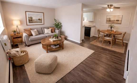 A living room with a couch, a chair, a table, and a potted plant.