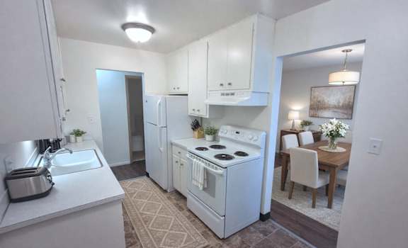 A small white kitchen with a sink, stove, and refrigerator.