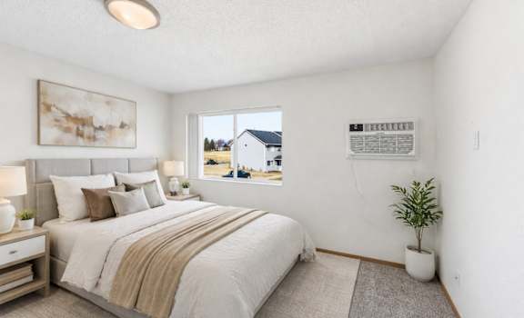 A bedroom with a large bed and a window overlooking a house.