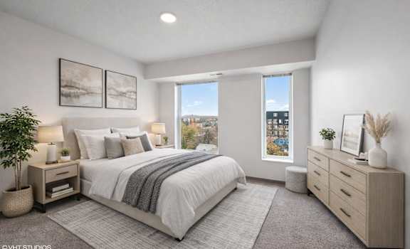 A bedroom with a large bed, a window with a view, and a nightstand with a plant on it.