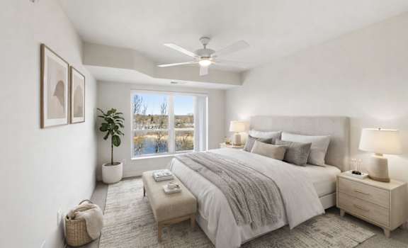 A well-lit bedroom with a large bed, a nightstand, and a window overlooking a snowy landscape.
