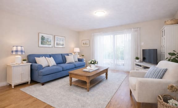 A living room with a blue couch, a wooden coffee table, and a white armchair.