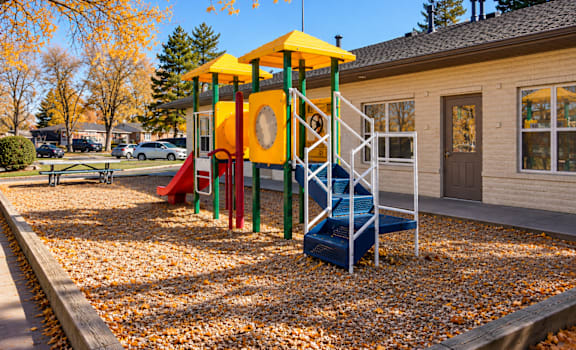 A playground with a yellow and green structure and a blue slide.