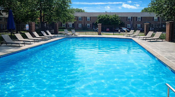 A large blue swimming pool surrounded by lounge chairs.