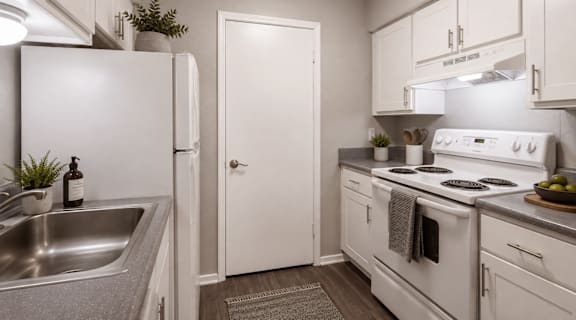A white kitchen with a sink, refrigerator, and stove.