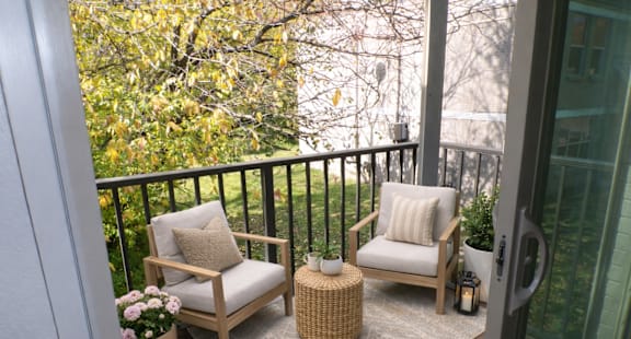 A balcony with two chairs and a table.