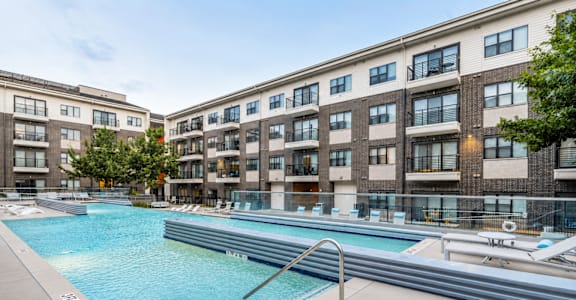 A swimming pool in front of a building with a metal ladder.