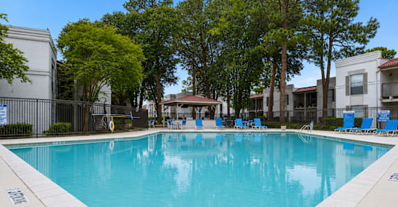 A large swimming pool surrounded by trees and chairs.