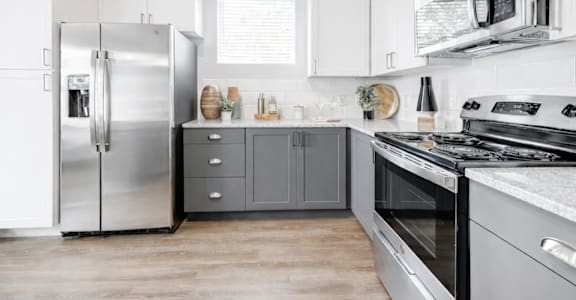 A modern kitchen with a stainless steel refrigerator, oven, and microwave.