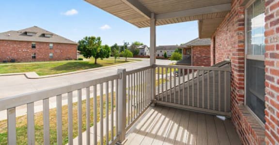 A porch with a white railing and a wooden floor.