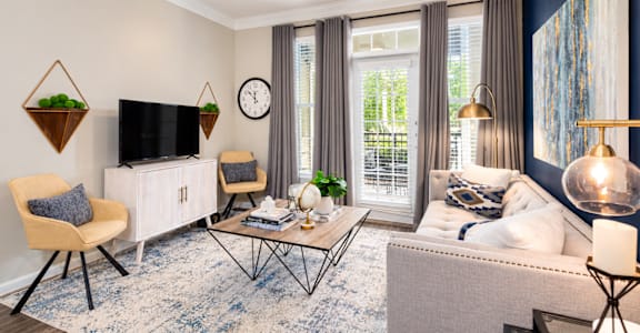 A living room with a white sofa, a wooden chair, a TV, and a rug.