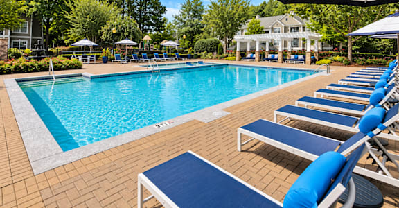 A pool with blue chairs and a white umbrella.