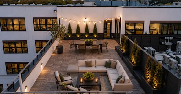 A rooftop patio with a couch, chairs, and string lights.