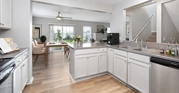 A kitchen with white cabinets and a wooden floor.