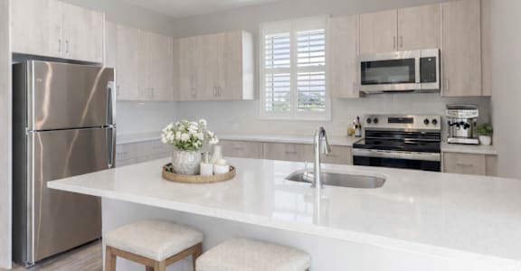 Open-concept kitchen featuring quartz-style countertops, large island seating area, and stainless steel appliances at Creekline at Fairfield apartments, Fairfield CT.