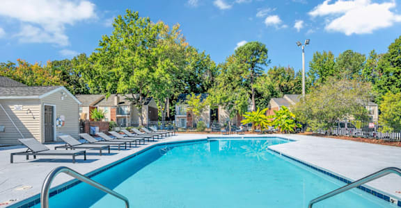 A swimming pool surrounded by trees and a clear blue sky.