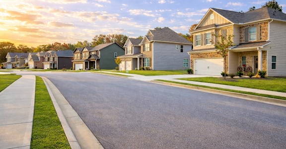 A row of houses with a sidewalk in front of them.